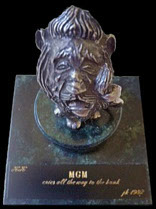 Photo of Wizard of OZ Cowardly lion statuette on a marble base with caption: KK - MGM cries all the way to the bank- 1982 